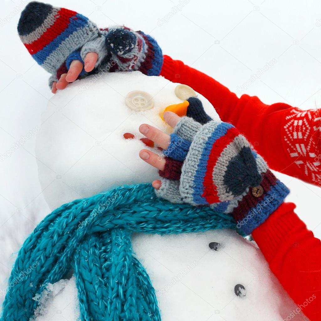 Hands Building Snowman Outside in Winter