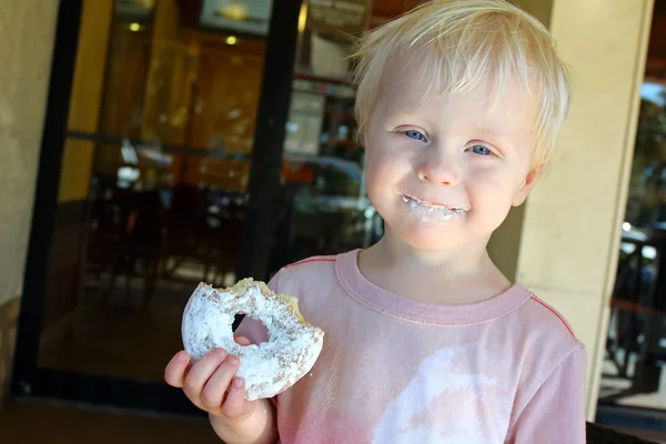 Щасливі маленької дитини їдять пончик в кафе — стокове фото