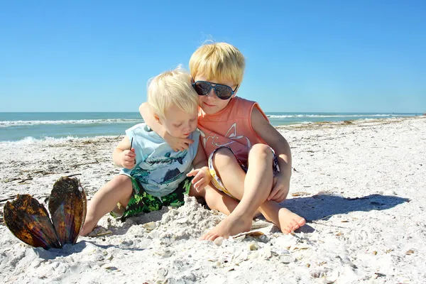 Двое маленьких детей обнимаются на пляже — стоковое фото