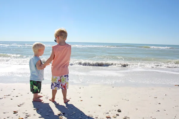 Broers hand in hand op het strand — Stockfoto