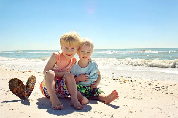 Hermanos jóvenes abrazándose en la playa por el océano —  Fotos de Stock