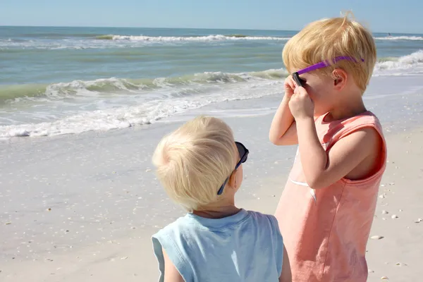 Baby broer kijken ouder kind op strand — Stockfoto