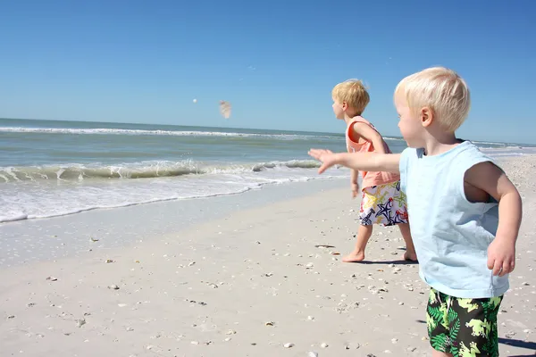 Dzieci rzucanie muszle do oceanu — Zdjęcie stockowe