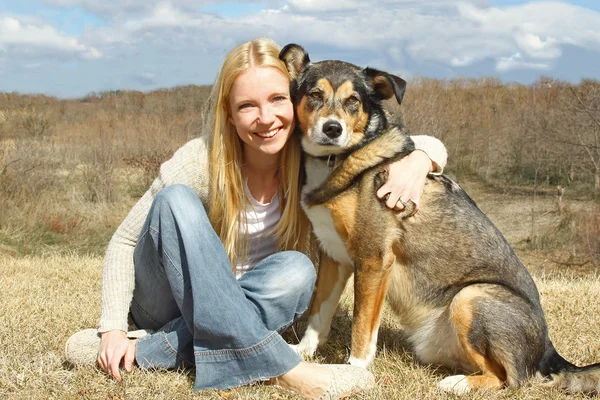 Frau und Hund umarmen sich draußen auf dem Land — Stockfoto