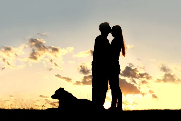 Älskande par kyss vid solnedgången siluett — Stockfoto