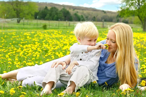 Anne ve genç çocuk çiçek çayır rahatlatıcı — Stok fotoğraf