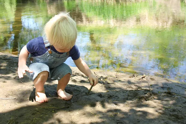 Malé dítě hraje v bahně řeky — Stock fotografie
