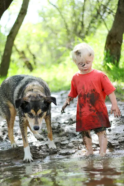 Criança e cachorro brincando em Muddy River — Fotografia de Stock