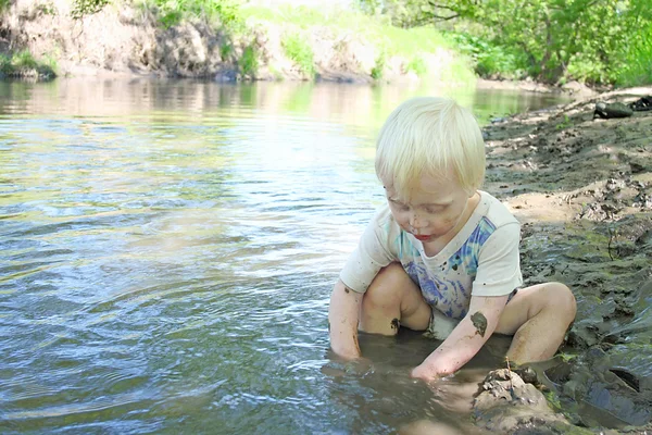 Jong kind zit in de rivier in de zomer — Stockfoto