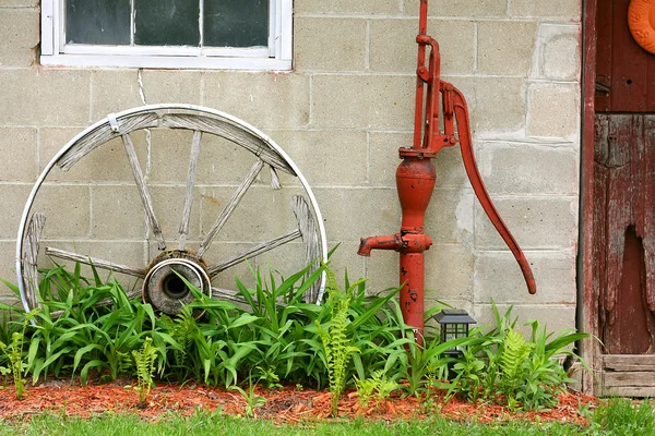 Roda de madeira antiga do vagão e bomba de água pelo celeiro — Fotografia de Stock