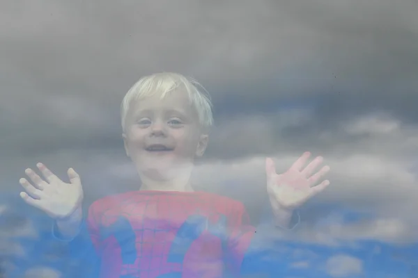 Счастливый маленький ребенок, выглянувший из окна — стоковое фото
