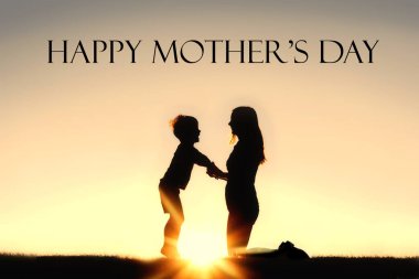 Gökyüzünde bir gün batımı önünde onun mutlu küçük çocuk ile el ele tutuşan genç bir annenin silueti.