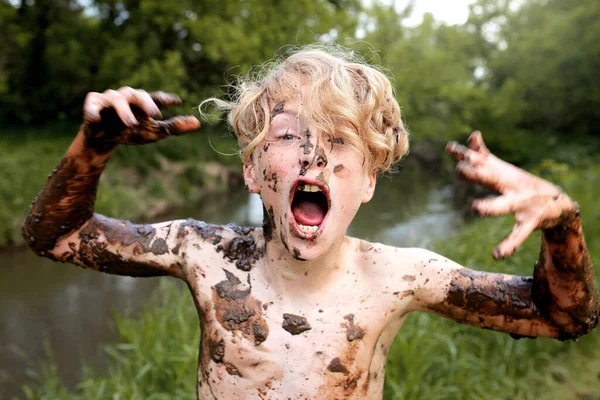 Wild Kid Happily Yelling While Covered Mud Swimming River 免版税图库图片