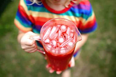 Bir çocuk elinde bir sürahi buz ve kırmızı meyve suyu karışımı tutuyor..