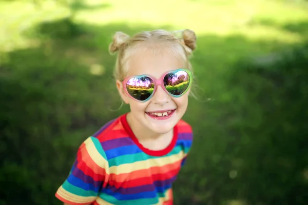 Uma Menina Feliz Está Sorrindo Fora Enquanto Brinca Óculos Sol — Fotografia de Stock
