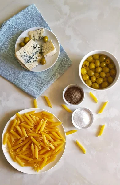 İtalyan mutfağı ve İtalyan yemekleri konsepti. Makarna, gorgonzola, zeytin, tuz, hafif arkaplanda biber. Üst görünüm