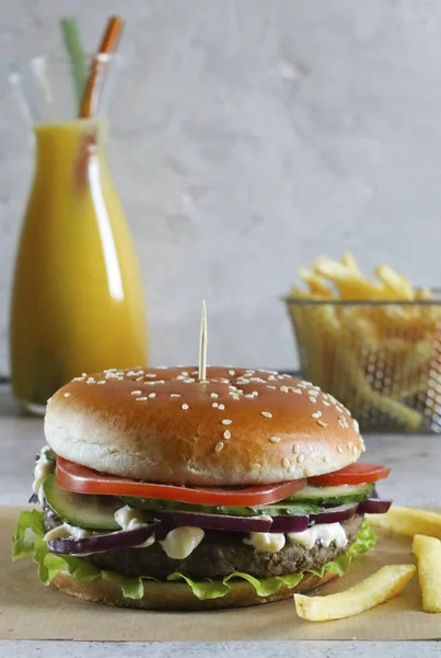 Hafif bir arka planda kızarmış patates ve portakal suyu ile hamburger.