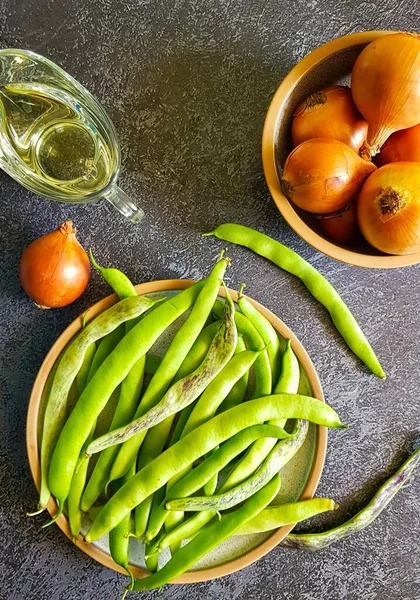 Taze fasulye, soğan ve koyu arkaplanda zeytin yağı..