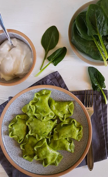 Green dumplings with cottage cheese and spinach on ceramic plate with gray textiles. — Stock Photo, Image