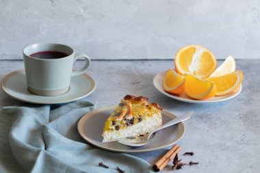 Turuncu dolgulu bir parça turta, bir fincan çay, açık arkaplan, gri tekstil