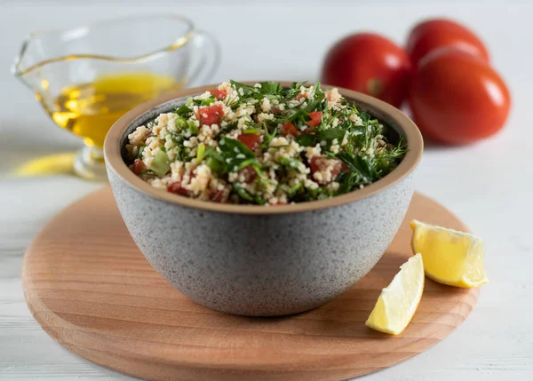 Ceramic bowl of Arabic salad Tabbouleh on a wooden board, side view — Stockfoto