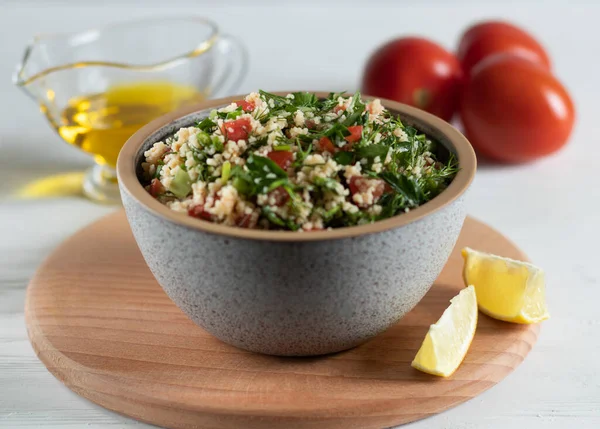 Ceramic bowl of Arabic salad Tabbouleh on a wooden board, side view