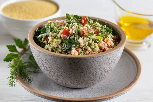 gray ceramic bowl of Arabic salad Tabbouleh on a ceramic plate, side view