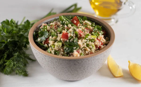 Gray ceramic bowl of Traditional Arabic salad Tabbouleh, side view, close-up