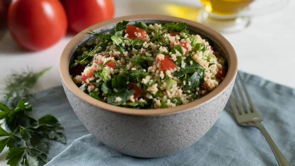 Traditional Arabic salad Tabbouleh on a white background with gray textiles — Stockfoto