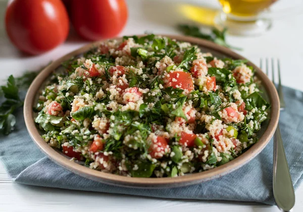 Plate of Arabic salad Tabbouleh on white background with gray textiles and fork — Stockfoto