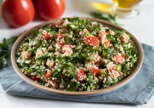 Ceramic plate of Arabic salad Tabbouleh on a white background with gray textiles — Fotografie, imagine de stoc