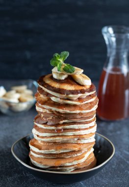Akçaağaç şuruplu krep yığını, siyah tabakta muz.
