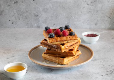 Yaban mersinli waffle, ahududu ve ballı açık beton zemin