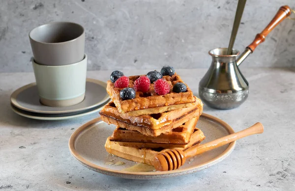 Böğürtlenli waffle, bal, jezva ve bardaklar açık beton arka planda