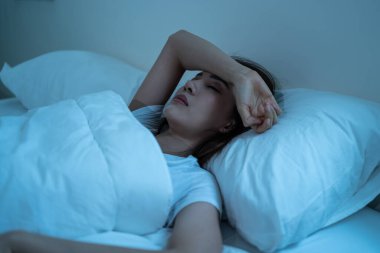 Karanlık bir gecede pijamalı Asyalı sinirli kız yatakta uyanık yatıyor. Çekici, güzel, depresyonda, üzgün, endişeli ve endişeli genç bir kadın yatak odasında uykusuzluktan uyuyamıyor..