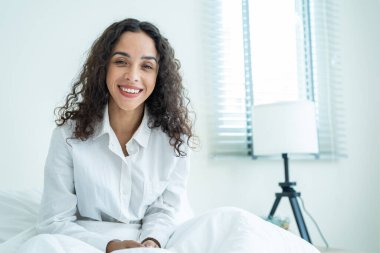 Pijamalı güzel bir kızın portresi gülümsüyor ve kameraya bakıyor. Çekici genç bir kadın, sabahları yataktan erken kalktığı için mutlu ve zinde hissediyor. sağlıklı yaşam tarzı kavramı.