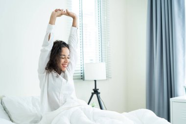 Pijamalı güzel Latin kız sabah mutlulukla uyanıyor. Çekici genç bir kadın gülümsüyor, mutlu ve rahat hissediyor. Sonra da yatak odasında uyuduktan sonra vücudunu esnetiyor..