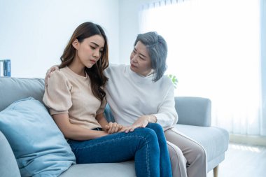 Asyalı sevgi dolu yaşlı anne, sorun için ağlayan kızını rahatlatıyor. Yaşlı anne desteğini önemsemek, teselli etmek ve evde göz yaşları içinde stresli genç bir kadına empati kurmak. Aile ilişkisi.