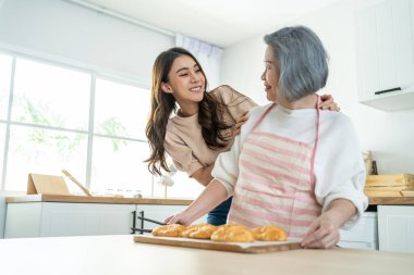Asyalı sevimli aile, genç kız mutfakta yaşlı aşçıya bakıyor. Güzel dişiler boş zamanlarını harcayıp yaşlı annelerine sarılmaktan ve evde kruvasan pişirmekten hoşlanırlar. Etkinlik ilişkisi