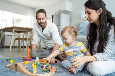 Beyaz, mutlu bir ebeveyn, bebek bebekle oturma odasında oynuyor. Çekici bir çift anne ve baba, küçük bir çocuğun gelişimine bakıyor. Evde etkinlik ilişkisi.