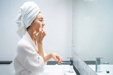 Asyalı güzel kadın yüz bakımı için yumuşak ve cilt bakımı yapıyor. Çekici kadın dokunuşları ve gençleşme için krem sürme duştan sonra nazikçe. Güzellik, cilt bakımı ve sağlık