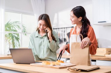 Asyalı güzel iş kadını ve arkadaşı evde fırın ve satış yapıyorlar. Çekici lezbiyen çift, girişimcilikte başarılı oldukları için mutlu ve heyecanlı hissediyorlar. Evlerinden yemek siparişleri satıyorlar, sonra da beşlik çakıyorlar.