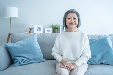 Portrait of Senior woman smile and look at camera in living room at home. Strong elderly older grandmother feeling happy and enjoy retirement life in house. Health care insurance and medical concept.