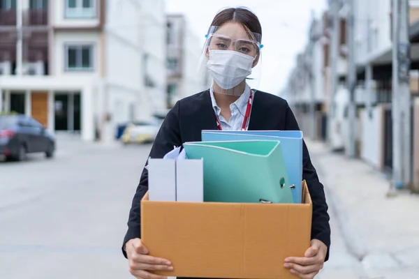 Asian business woman wear face mask after unemployment from company. Young attractive girl employee worker walking outdoor, feeling sad after losing the job due to world economic problem from covid 19