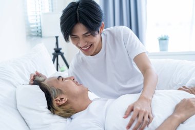 Asian handsome gay talk with boyfriend after wake up from sleep on bed. Atractive romantic LGBTQ man couple spend leisure time together in morning in bedroom in house. Homosexual-LGBTQ family concept.