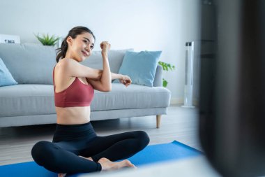 Asyalı genç, güzel, aktif bir kadın evde yoga pilates yapıyor. Spor giyim sektöründeki çekici kız mutlu ve rahatlamış hisset, evdeki oturma odasındaki çevrimiçi eğitmenin alıştırma videosunu izle.