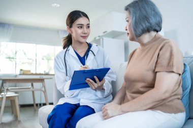 Asian caregiver psychology doctor examine and listen to woman patient. Young beautiful Woman nurse give advise and consult to help senior female solve problem at nursing home. Psychologic health care.