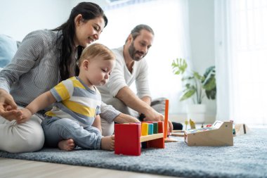 Beyaz, mutlu bir ebeveyn, bebek bebekle oturma odasında oynuyor. Çekici bir çift anne ve baba evde küçük bir çocukla vakit geçiriyor. Ev kavramında etkinlik ilişkisi.