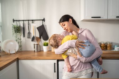 Caucasian loving mother hold baby boy toddler to lull him to sleep. Attractive mom carry little kid son with gentle and tenderness for healthy daytime nap in house. Motherhood-parenting concept.