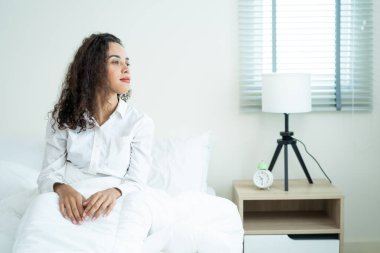 Portrait of Beautiful Latino girl in pajamas getting up with happiness. Attractive young woman feel fresh and happy to wake up early from bed in bedroom in morning at home. healthy lifestyle concept.